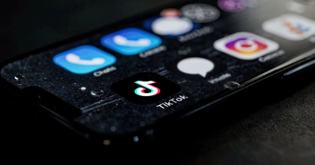 A close-up of a smartphone screen displaying the TikTok app icon among other social media and messaging apps.