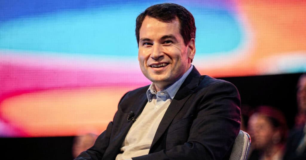 Tech speaker seated on stage at conference discussing Apple history book launch
