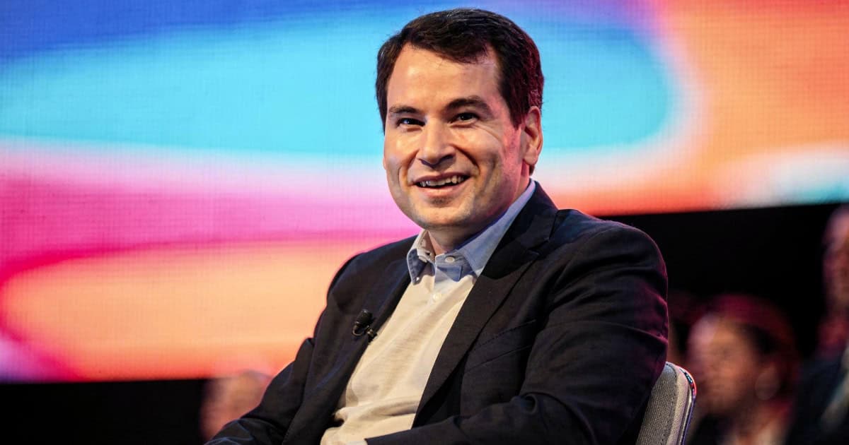 Tech speaker seated on stage at conference discussing Apple history book launch