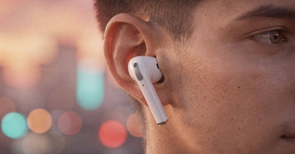 Close up of Apple AirPods worn in ear against blurred city background at sunset